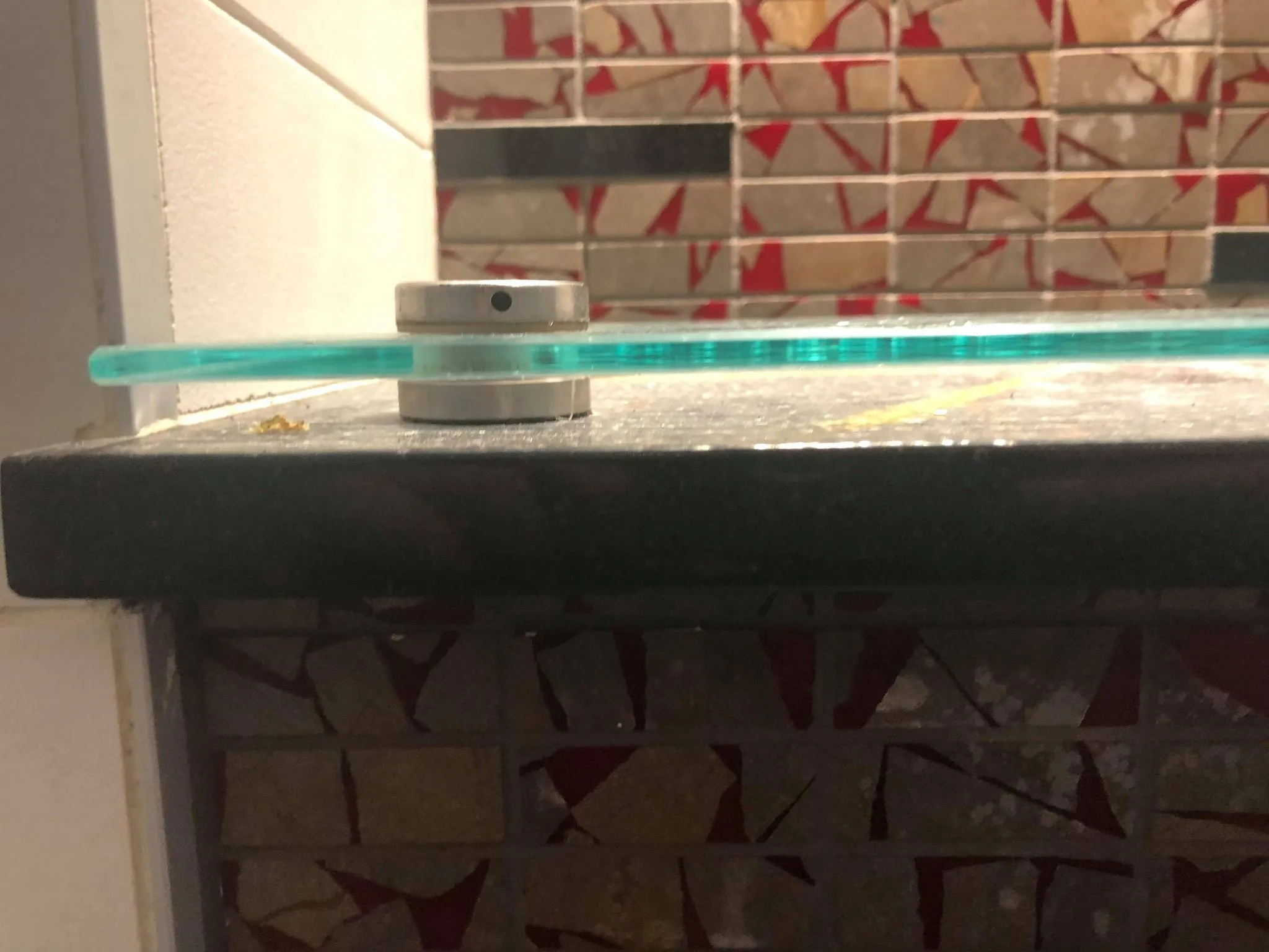 A glass plate resting on a stone shelf in the washroom